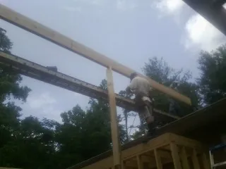 Carpenter setting a ridge beam over a new addition frame — Ice Dam Removal by Roofing Brothers in Bolckow