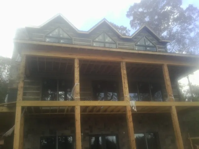 Dormers and porch framing on a large log home under construction — Roof Coating work by our crew in Bolckow