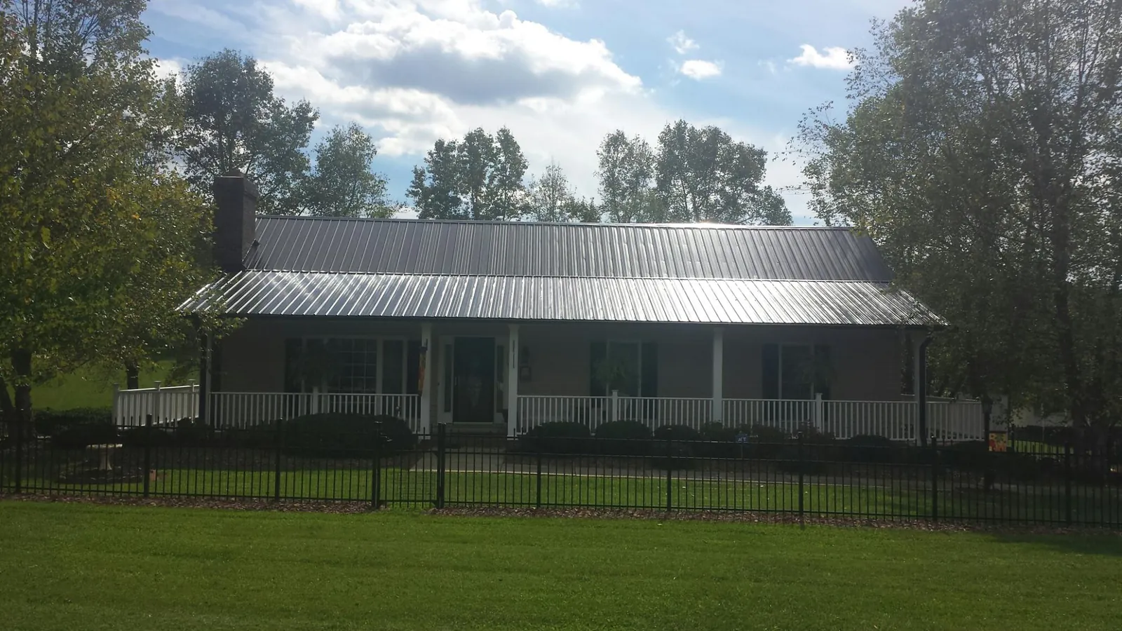 Gray metal roof on a brick ranch with a full width front porch — Gutter Guard Installation work by our crew in Bolckow